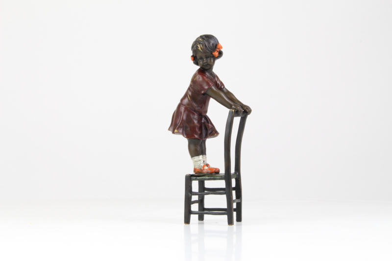 Bronzen meisje staand op stoel
