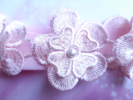 Smalle roze baby haarband met 5 kanten bloemen.