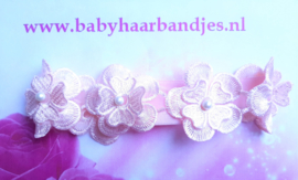 Smalle roze baby haarband met 5 kanten bloemen.