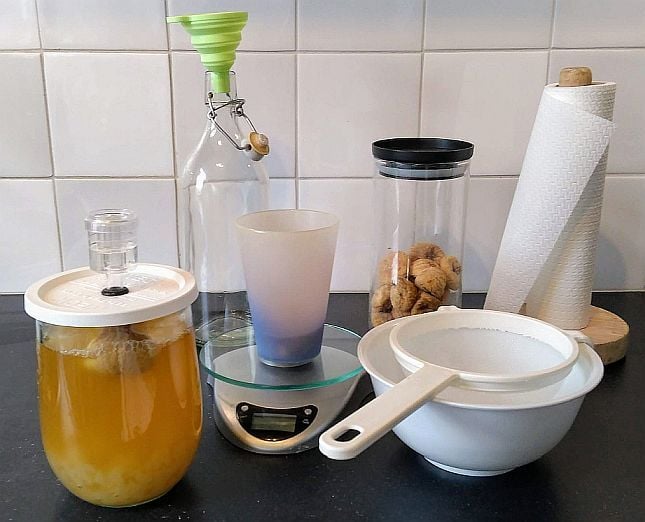 Kefir maken met waterkefirkorrels, kefir maken benodigdheden als fermentatiepot met waterslot en plastic kefir zeef.