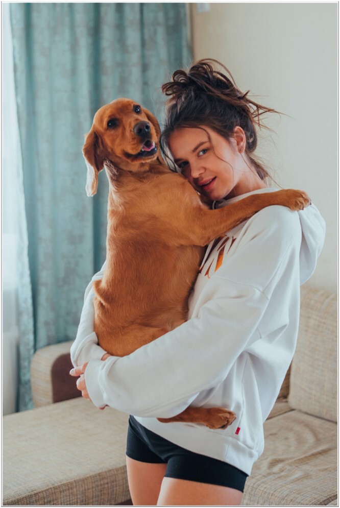 Meisje-in-jogging-houdt-grote-oranje-hond-in-armen