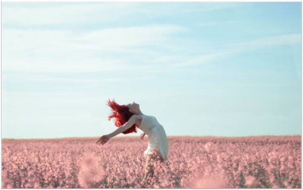 Rood-harige-vrouw-in-open-veld-met-blauwe-lucht