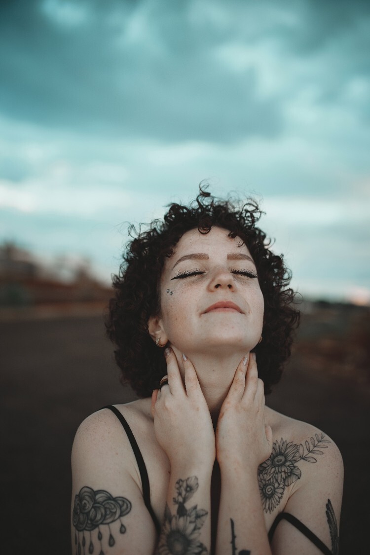 Vrouw met tatoeages en handen bij haar gezicht als beeld bij bevrijding en je stem vinden.