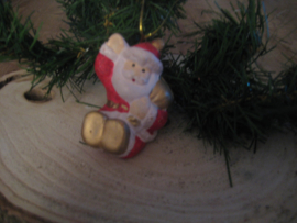 Zittende kerstman met zak over schouder