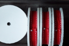 Band - rood met wit stiksel op wit houten spoel