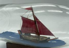 Een miniatuur Botter in glazen fles op houten standaard, L. 21 cm