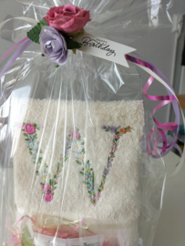 Cadeau geborduurd gastendoekje crème met bloemenletter en mini flesjes douche