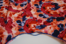 Een kapmanteltje van crêpe met een fantasie bloemmotief in de kleuren rood, oranje en blauw, met blauw biasband. Nog 1 op voorraad.