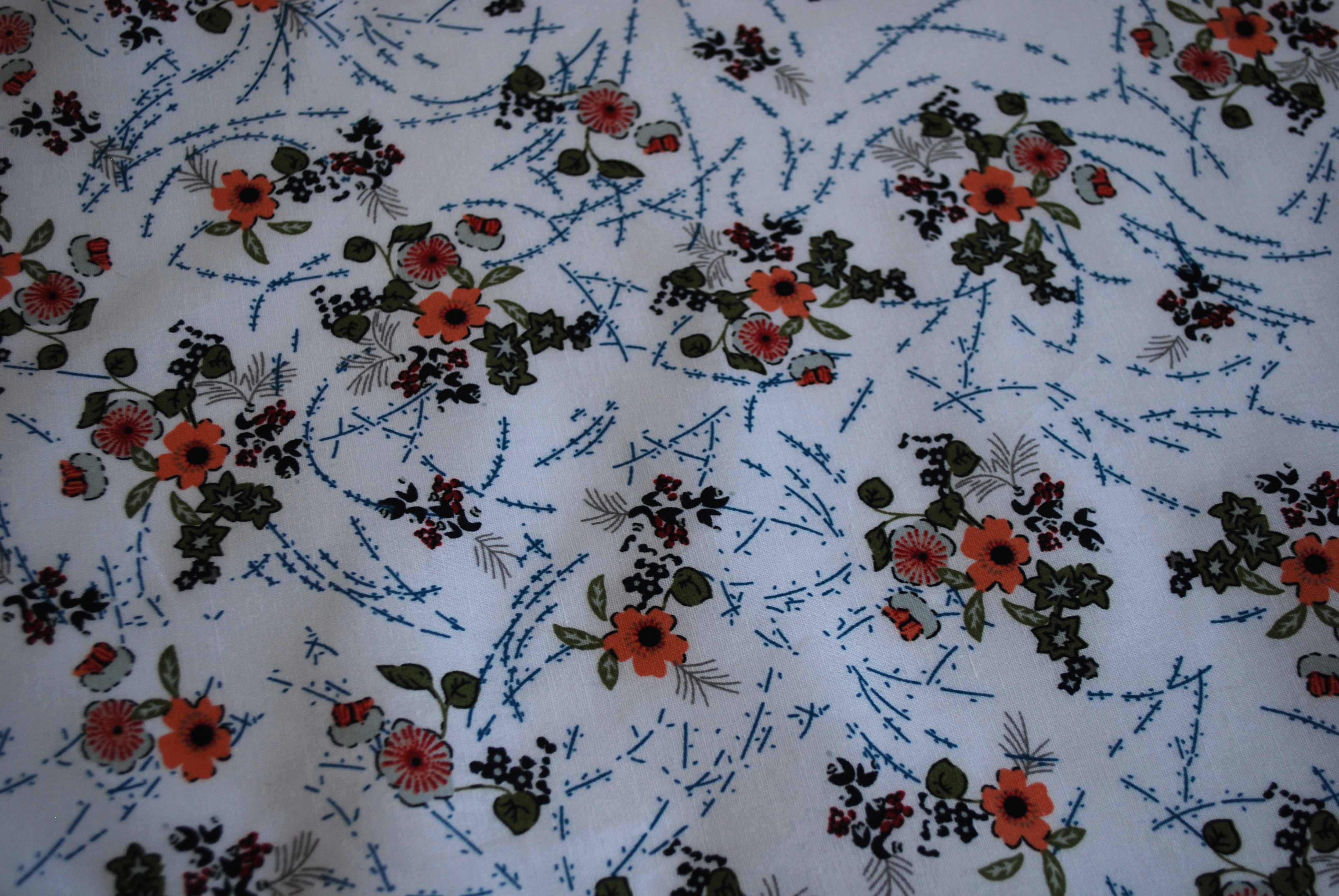 Een katoenen kapmanteltje met een lieflijk boeketje bloemen.