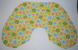 Een katoenen kapmanteltje met bloemen in diverse kleuren op een appeltjeskleurige ondergrond.