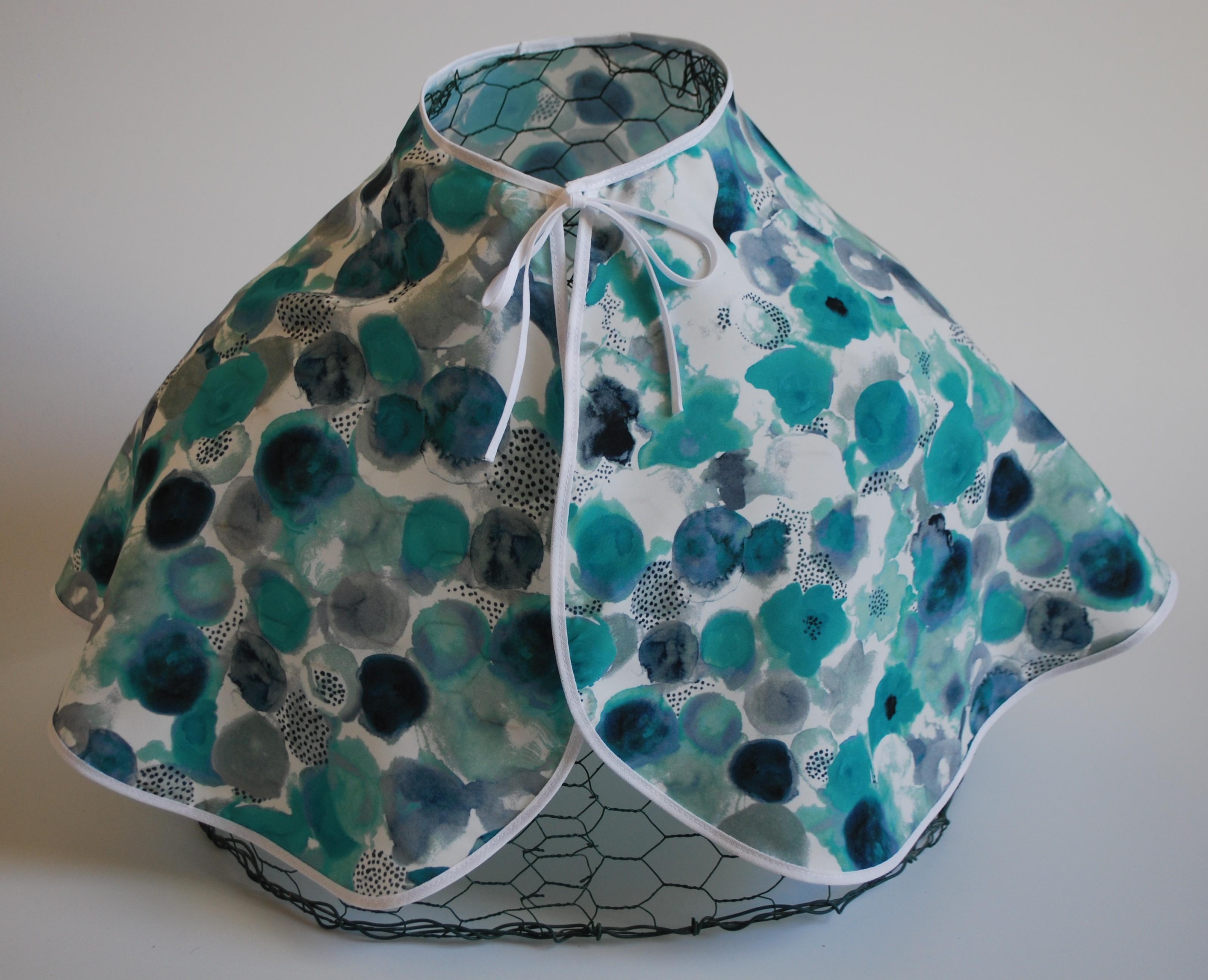 Een glad, zijdeachtig kapmanteltje van viscose met waterachtige bloemen in groen en blauw.