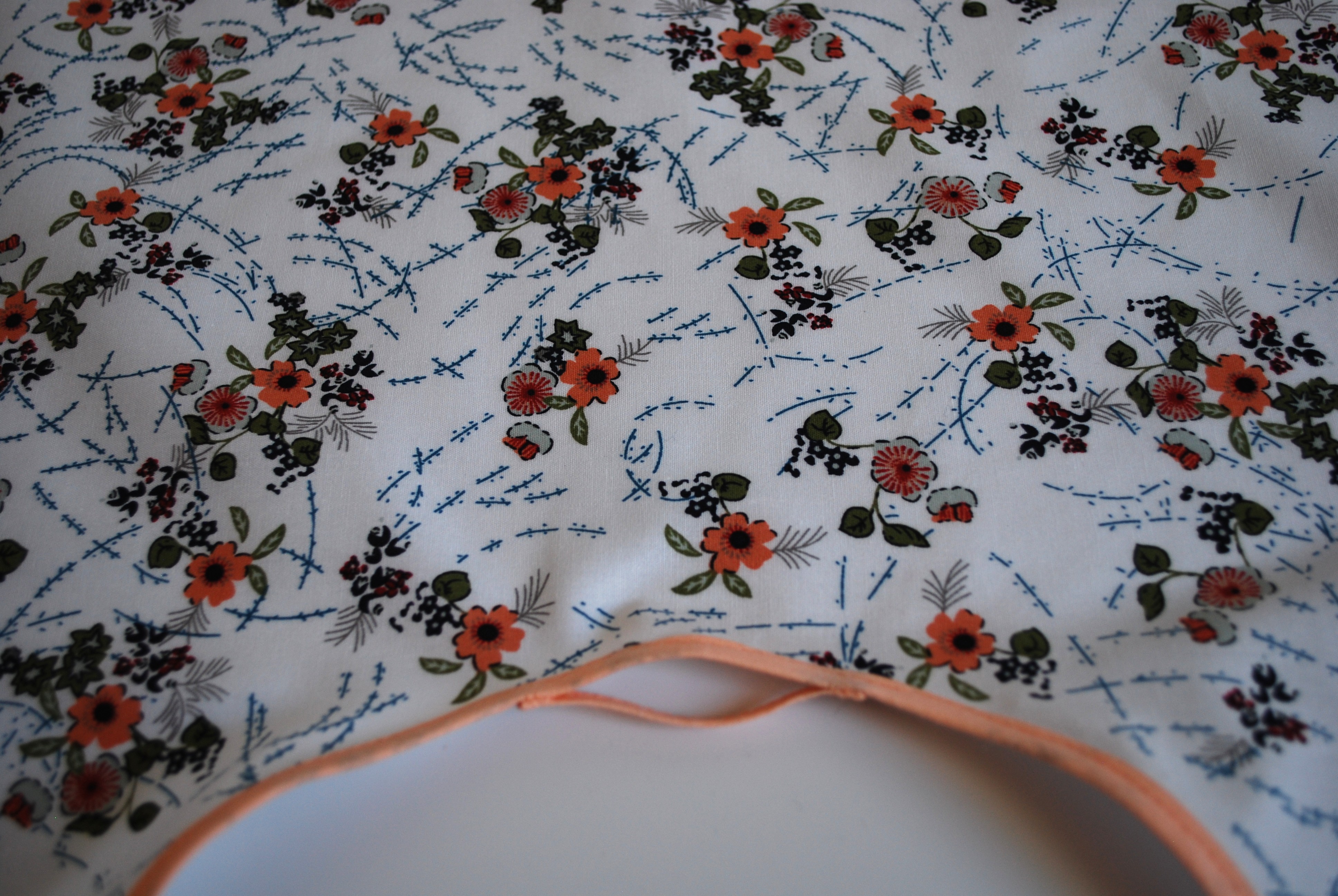 Een katoenen kapmanteltje met een lieflijk boeketje bloemen.