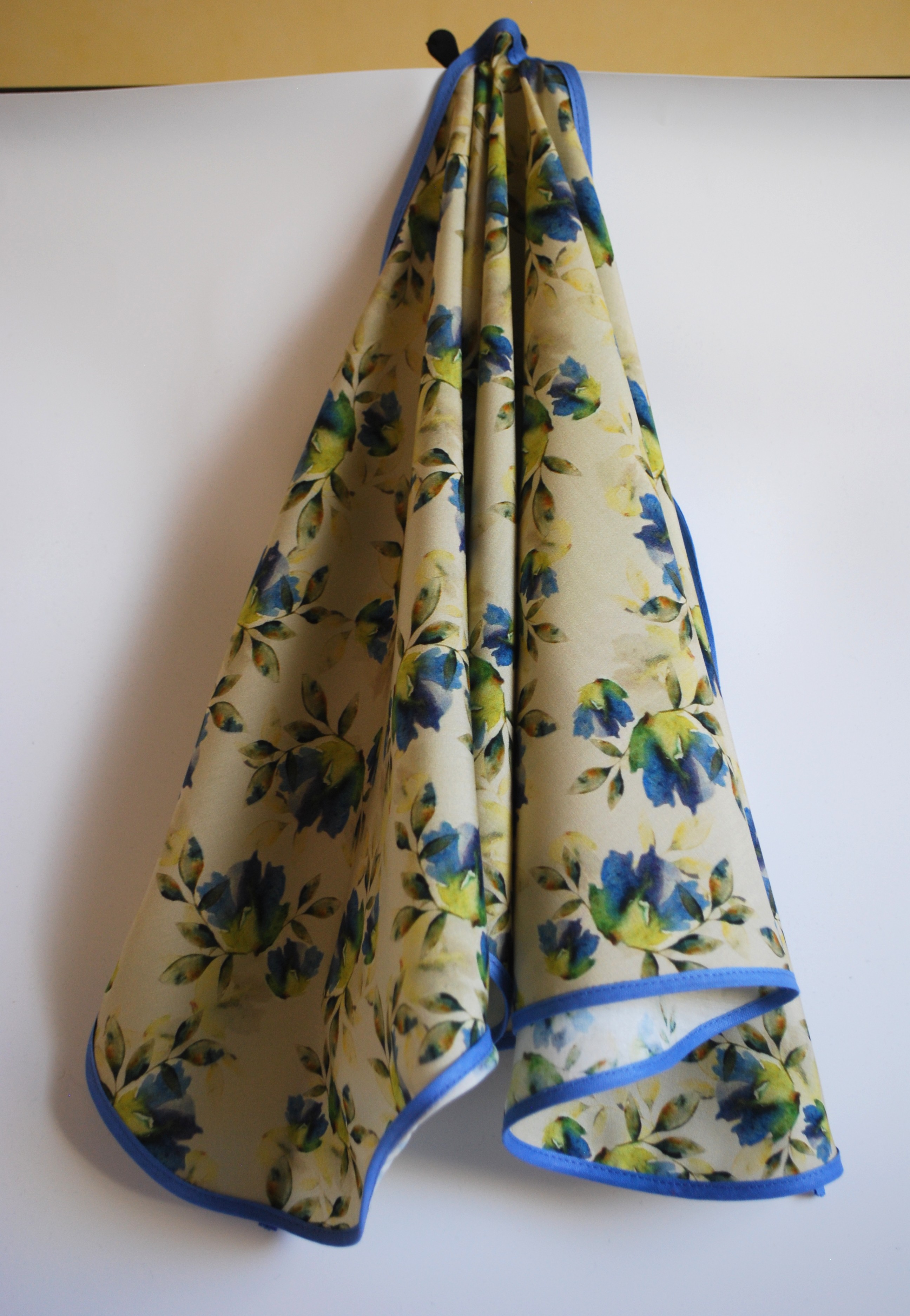 Een kapmanteltje van viscose met een boeketje van blauwe bloemen.