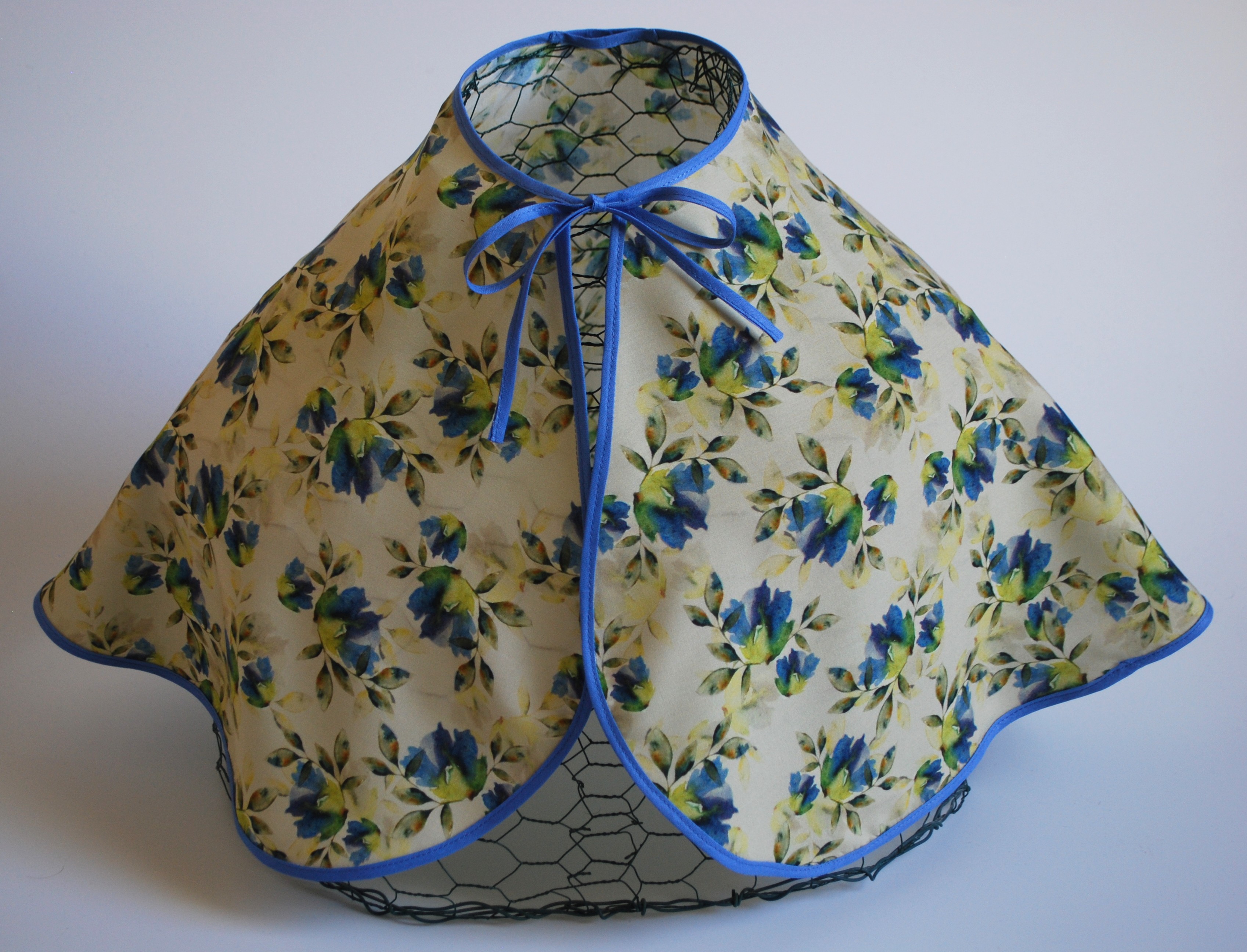 Een kapmanteltje van viscose met een boeketje van blauwe bloemen.