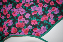 Een katoenen kapmanteltje van een crêpe stof met bloemen in roze, rood en paars. Nog 1 op voorraad.