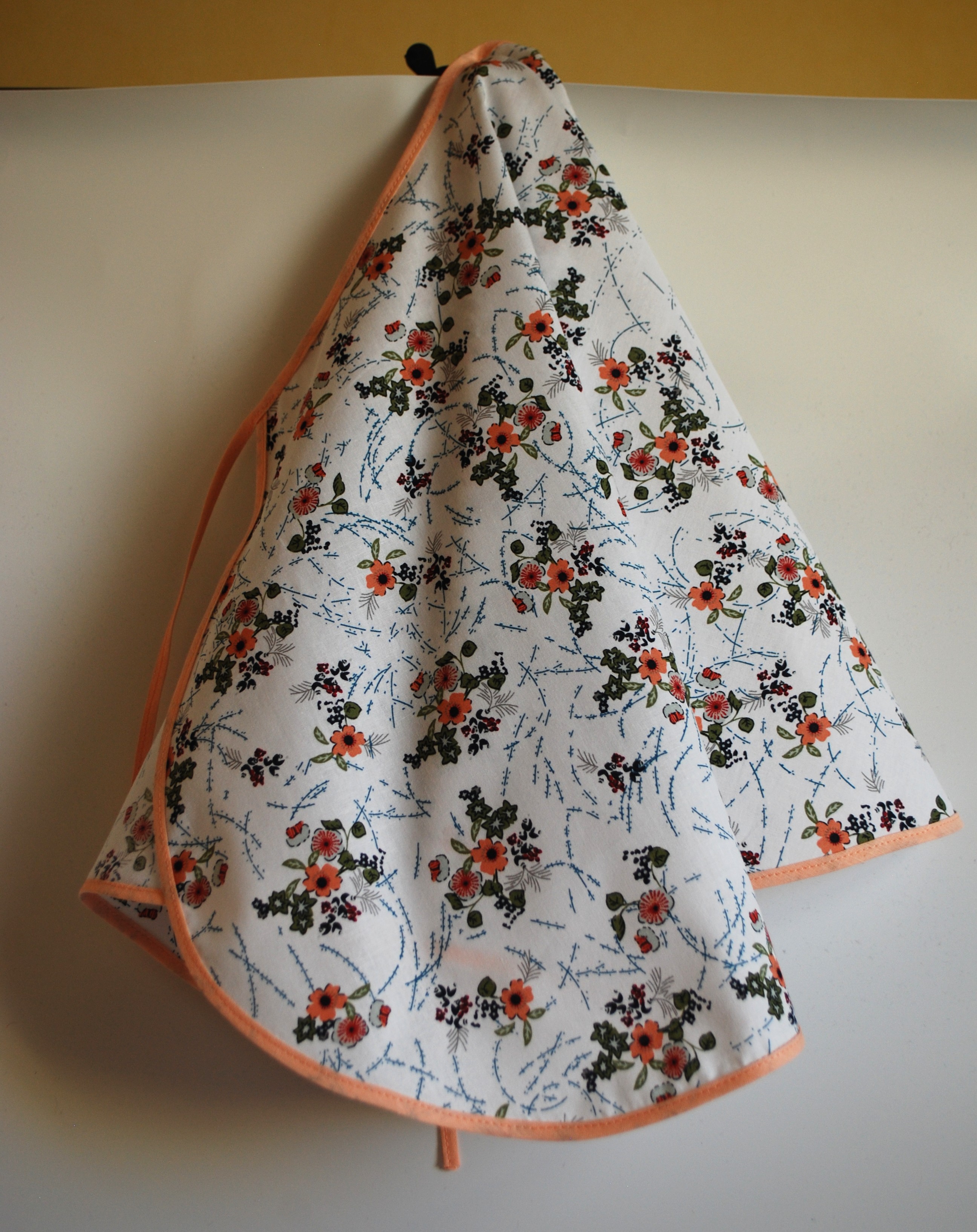 Een katoenen kapmanteltje met een lieflijk boeketje bloemen.