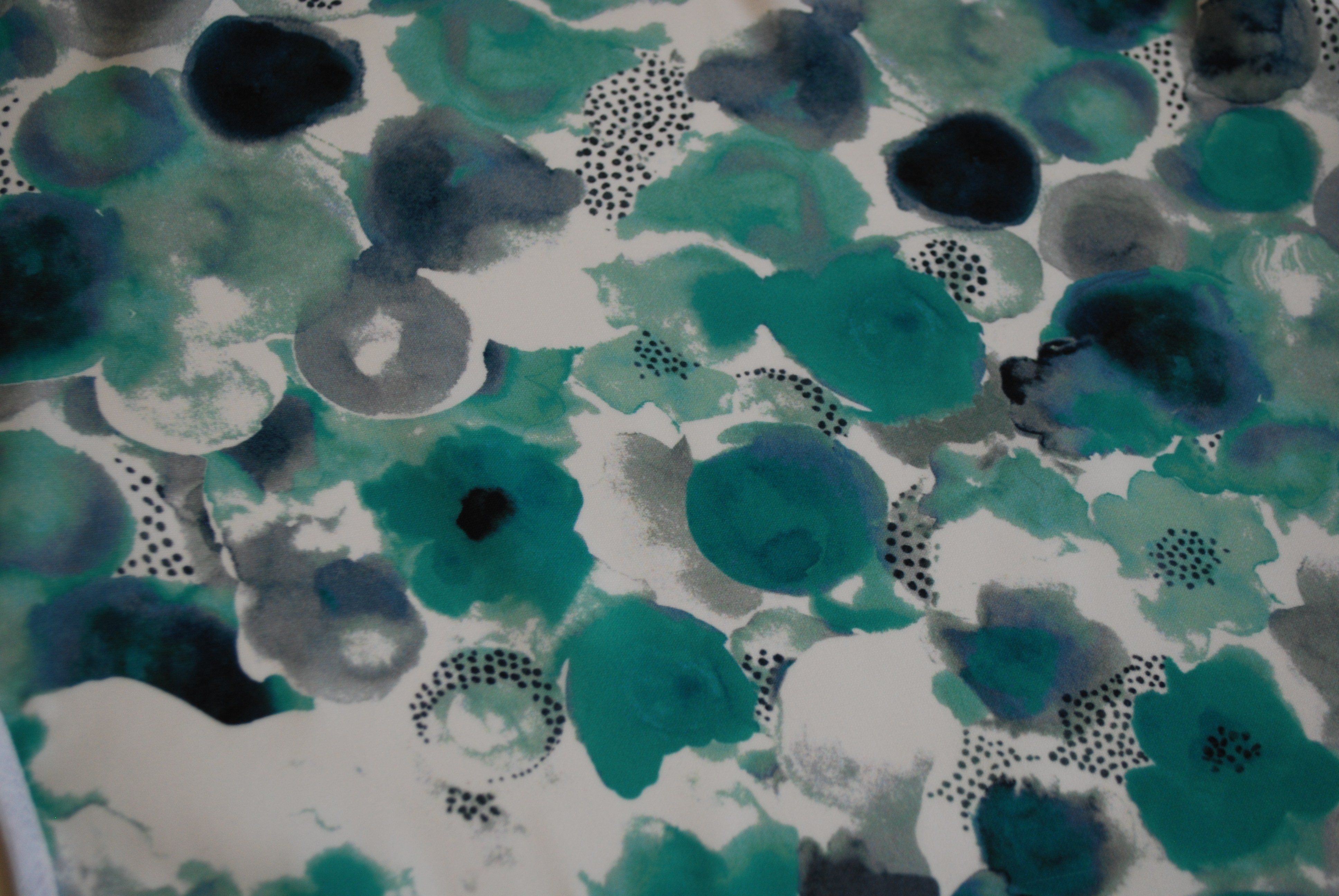 Een glad, zijdeachtig kapmanteltje van viscose met waterachtige bloemen in groen en blauw.