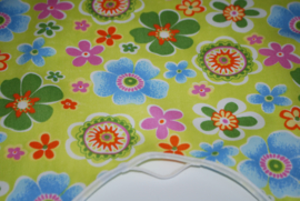 Een katoenen kapmanteltje met bloemen in diverse kleuren op een appeltjeskleurige ondergrond.