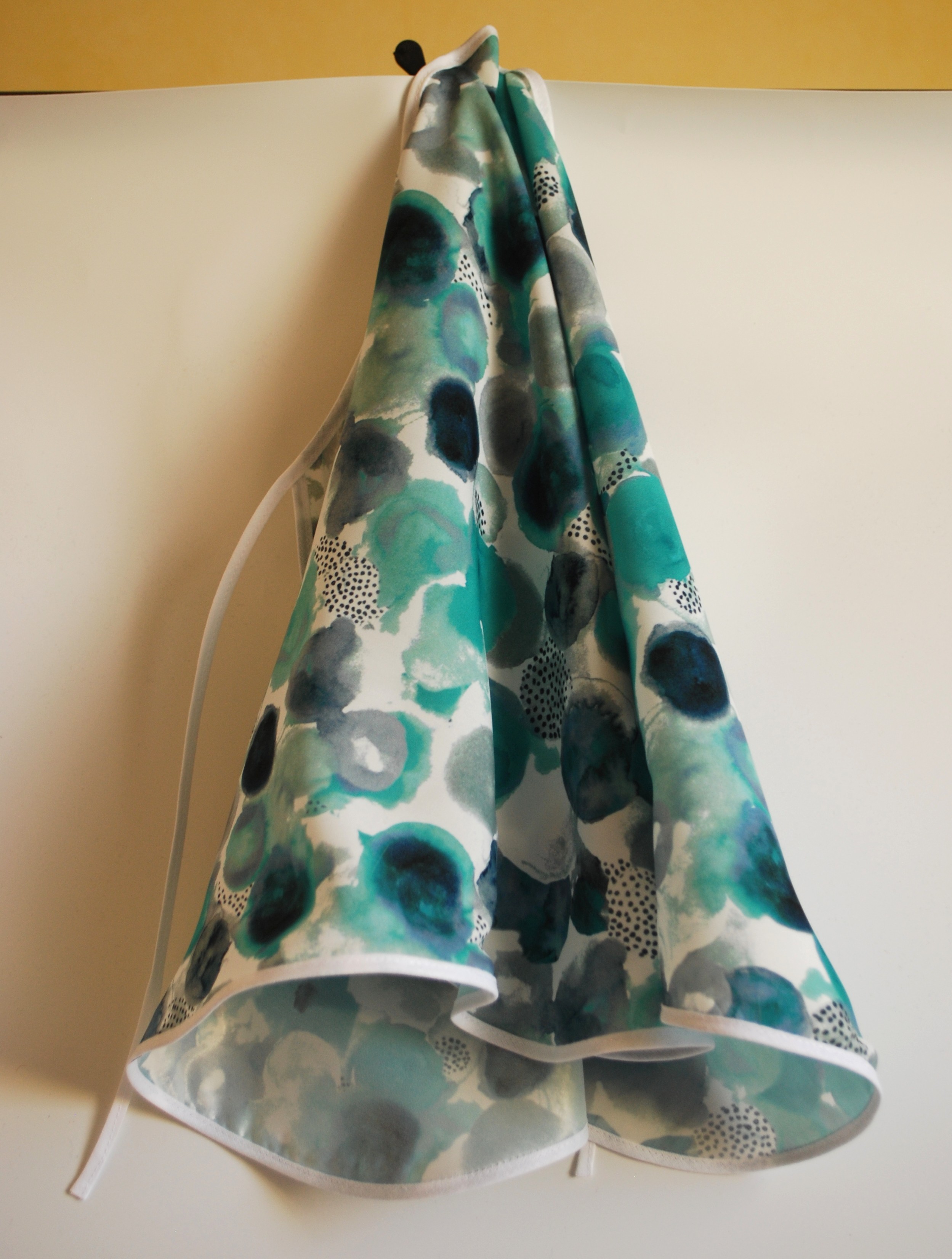 Een glad, zijdeachtig kapmanteltje van viscose met waterachtige bloemen in groen en blauw.