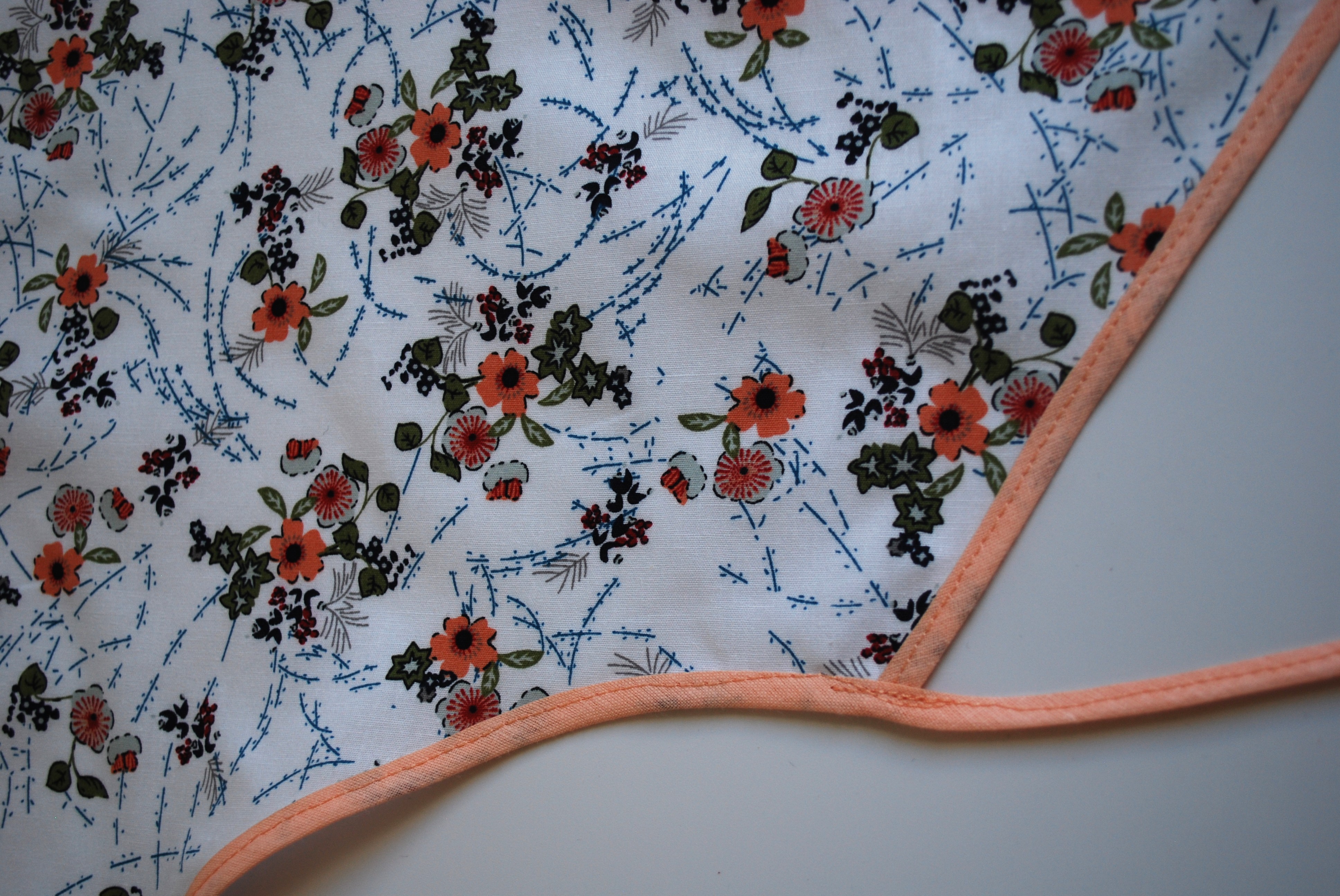 Een katoenen kapmanteltje met een lieflijk boeketje bloemen.
