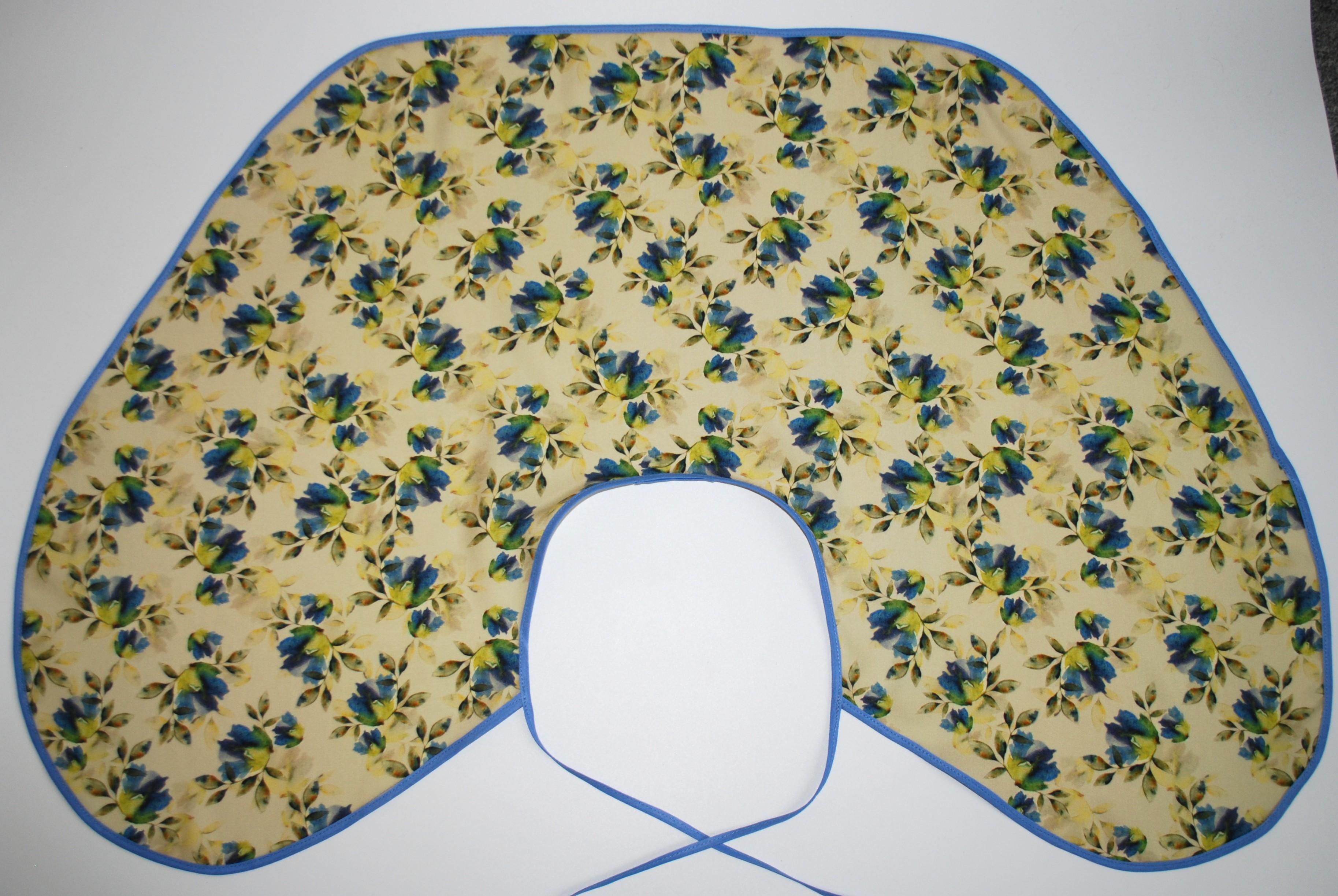 Een kapmanteltje van viscose met een boeketje van blauwe bloemen.