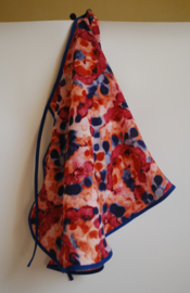 Een kapmanteltje van crêpe met een fantasie bloemmotief in de kleuren rood, oranje en blauw, met blauw biasband. Nog 1 op voorraad.