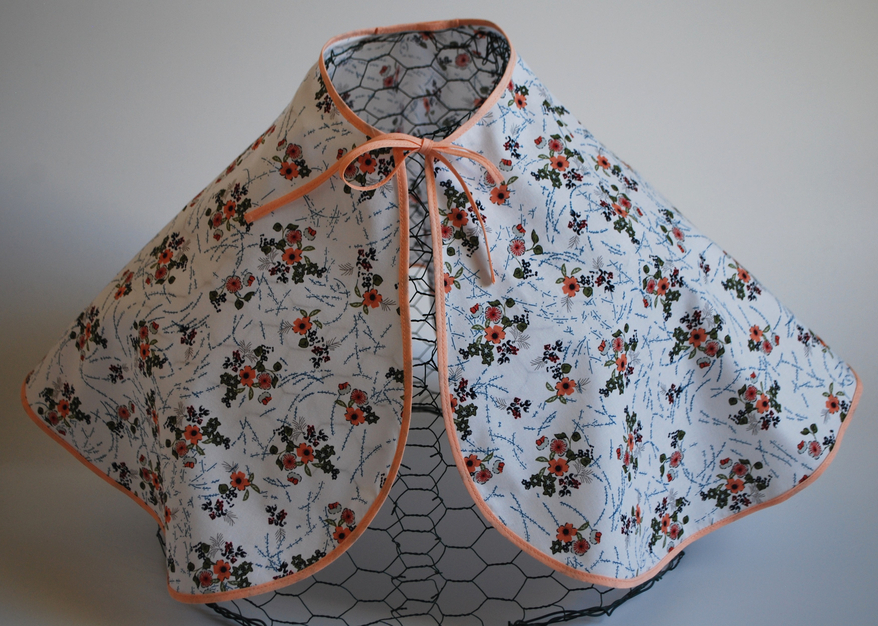 Een katoenen kapmanteltje met een lieflijk boeketje bloemen.