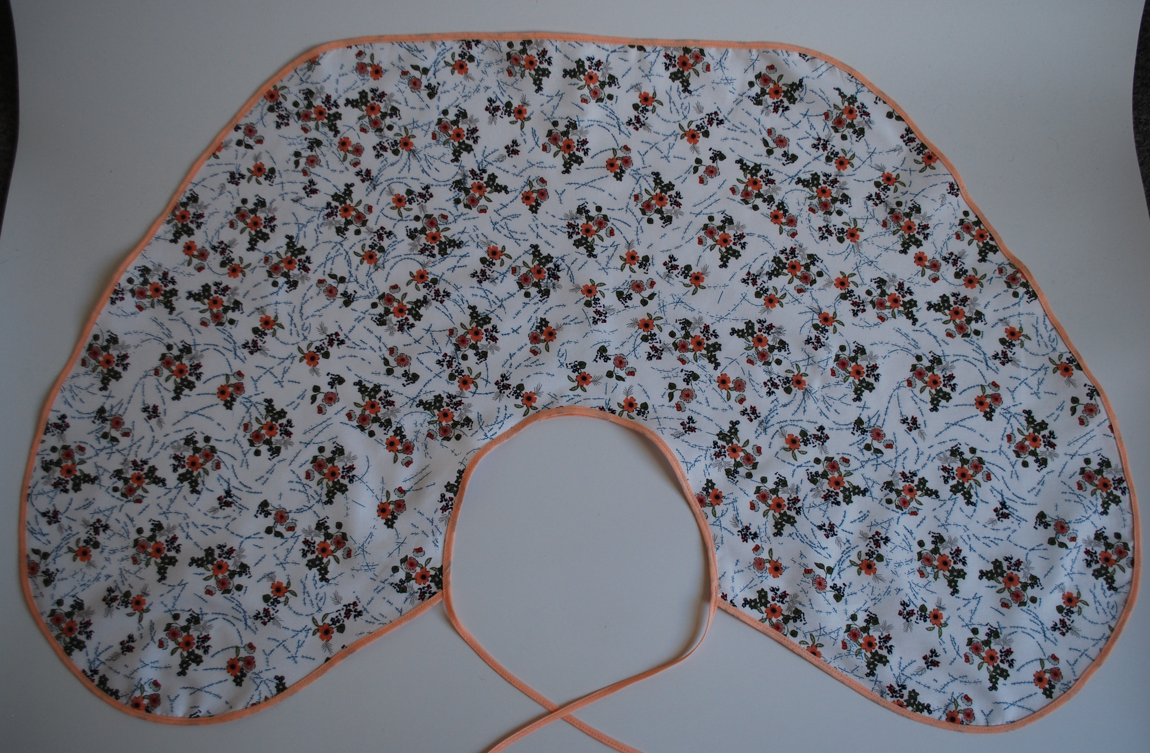 Een katoenen kapmanteltje met een lieflijk boeketje bloemen.