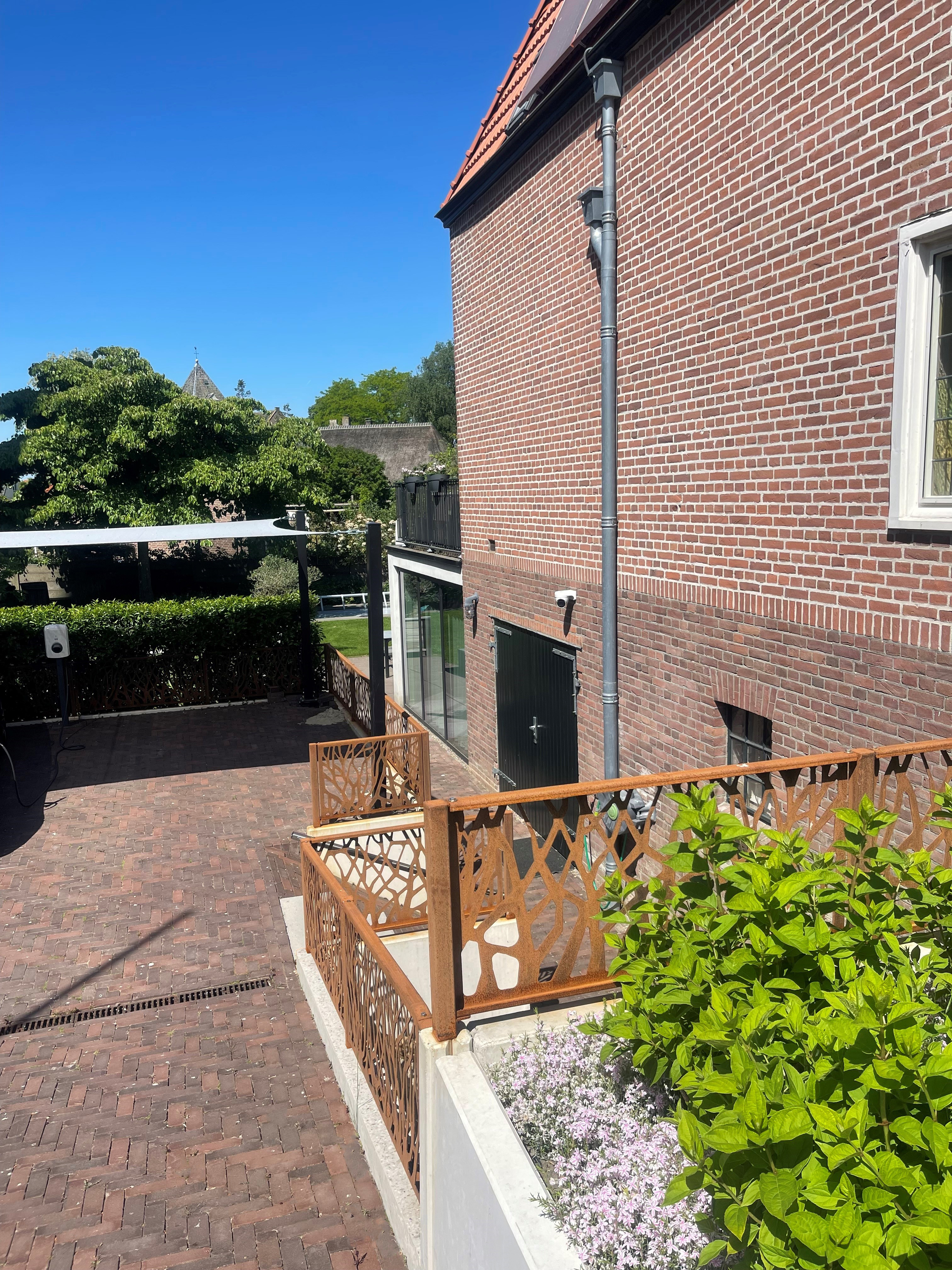 Sierhekwerk cortenstaal met boommotief bij Villa Maaszicht