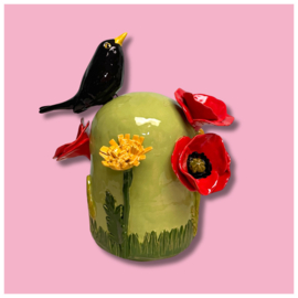 Kleine urn met bloemen en merel