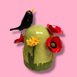 Kleine urn met bloemen en merel