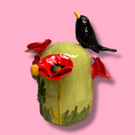 Kleine urn met bloemen en merel