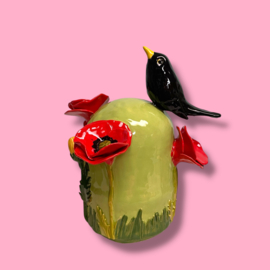 Kleine urn met bloemen en merel