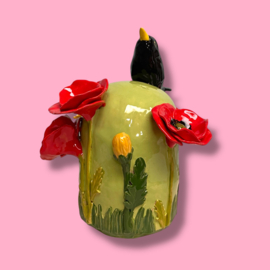 Kleine urn met bloemen en merel