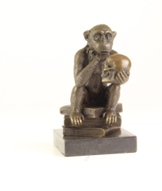 Bronzen chimpansee zittend op boeken