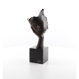 Een bronzen beeld van een gezicht dat op hand rust