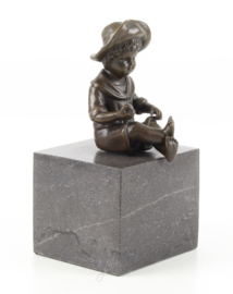 een bronzen jongen zittend op een marmeren sokkel
