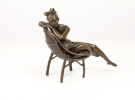 Bronzen beeld van meisje ontspannend in haar cirkel stoel.