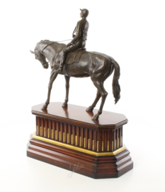 Een bronzen beeld van een jockey op paard op houten voet