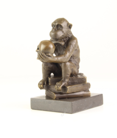 Bronzen chimpansee zittend op boeken