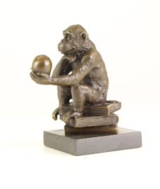 Bronzen chimpansee zittend op boeken