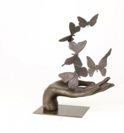 Bronzen beeld van een hand die vlinders loslaat