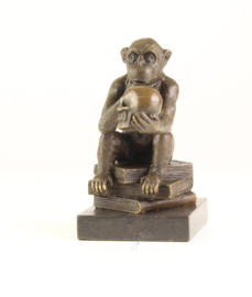 Bronzen chimpansee zittend op boeken