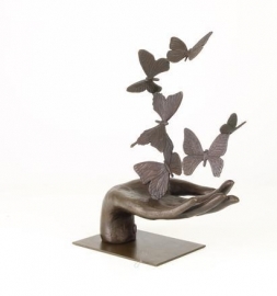 Bronzen beeld van een hand die vlinders loslaat