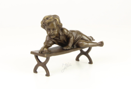 Schattig Bronzen beeldje van een kind met slak op de bank.