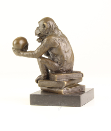 Bronzen chimpansee zittend op boeken