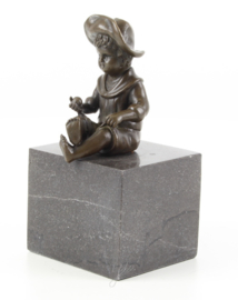 een bronzen jongen zittend op een marmeren sokkel