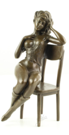 Bronzen Beeld van halfnaakte vrouw op stoel.