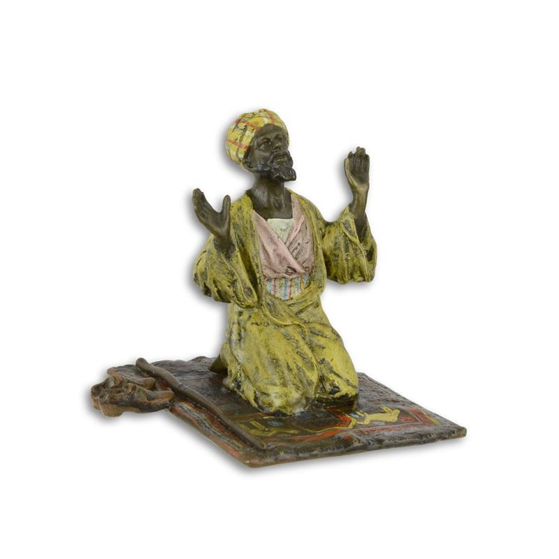 Een bronzen beeld van een Arabische man in gebed op tapijt