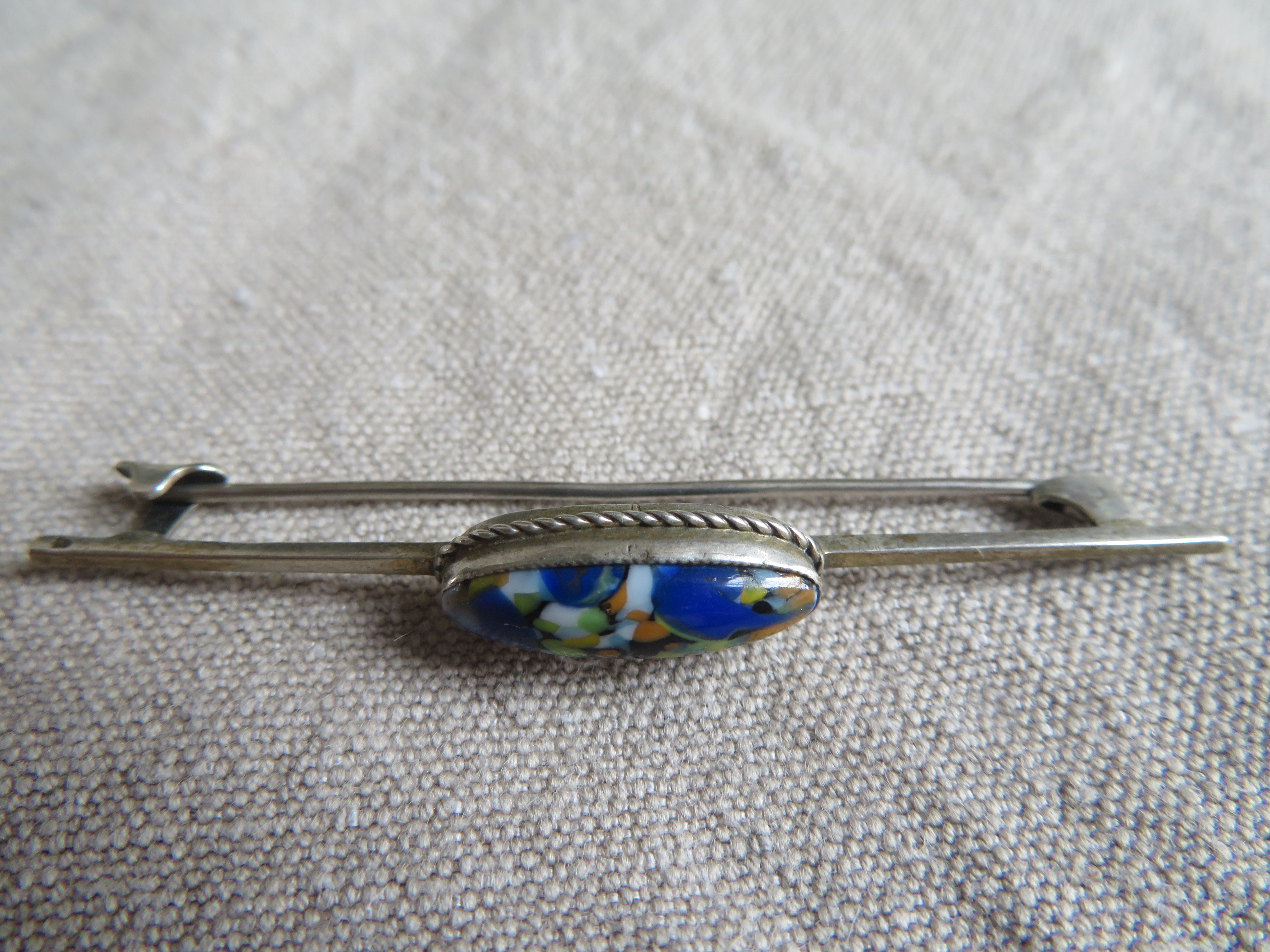 Verzilverde langwerpige broche met blauwe steen